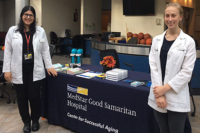 Two trainees pose next to a table in the Center for Successful Aging at MedStar Good Samaritan Hospital.