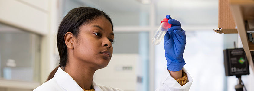 A researcher analyzes a vial in a lab.