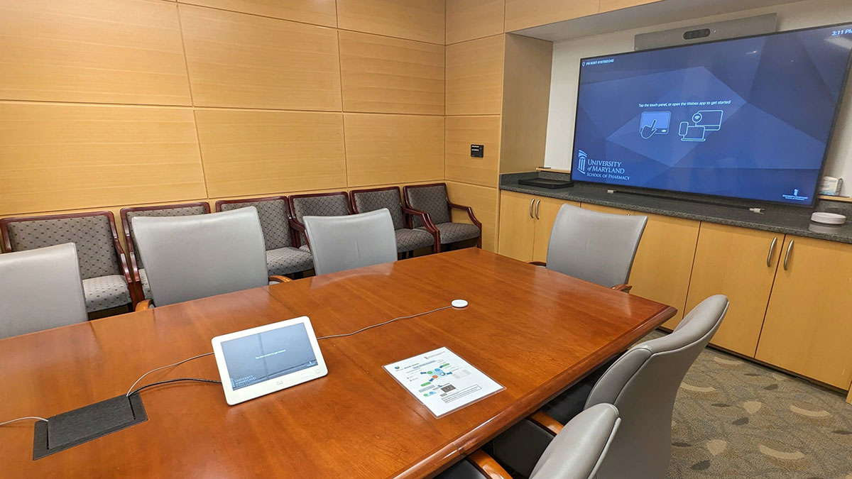 Dean’s conference room in Pharmacy Hall North, showing a large conference table, chairs, built‑in display screen, and guest seating along the wall.