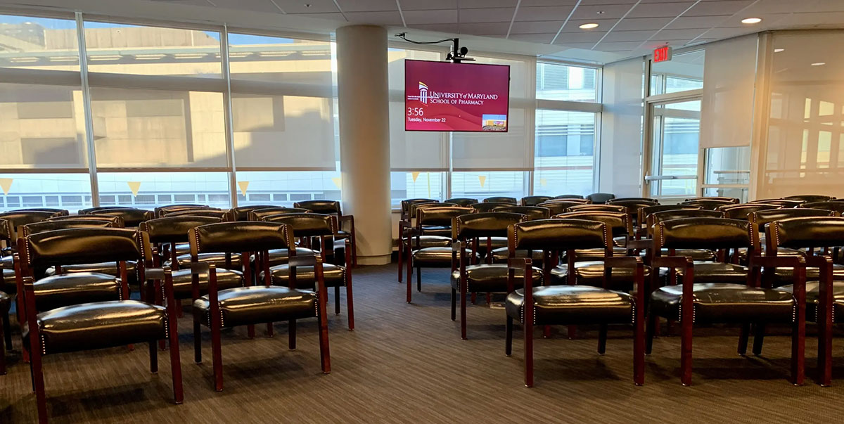 Alternate view of HSF 2‑600 showing rows of theater‑style seating facing a suspended presentation screen, with large windows along the side of the room.