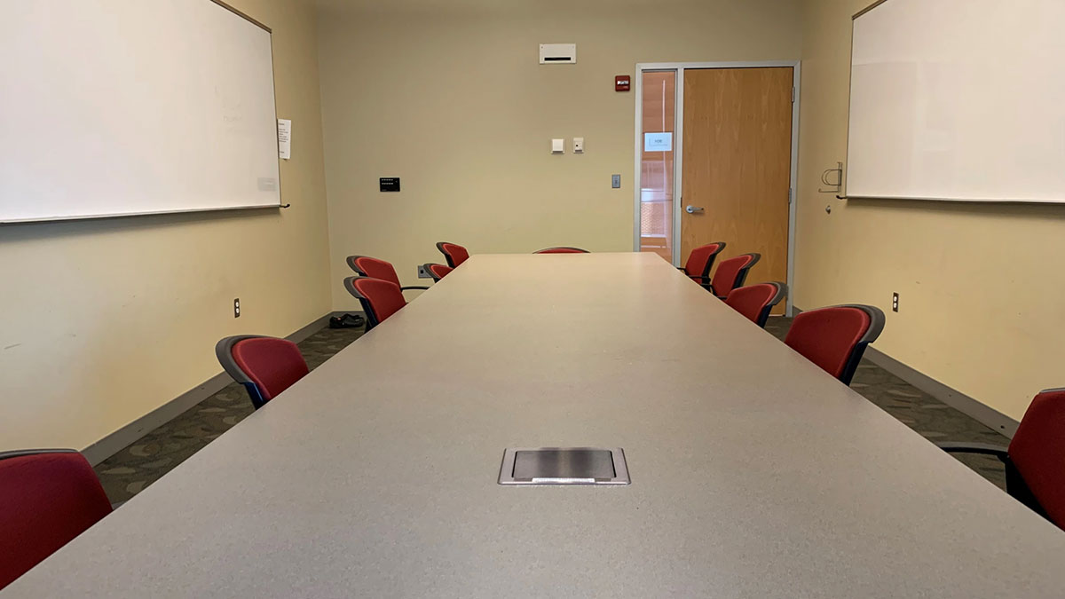 Seminar room in Pharmacy Hall North with a large central conference table, chairs arranged around it, and whiteboards mounted on the walls.