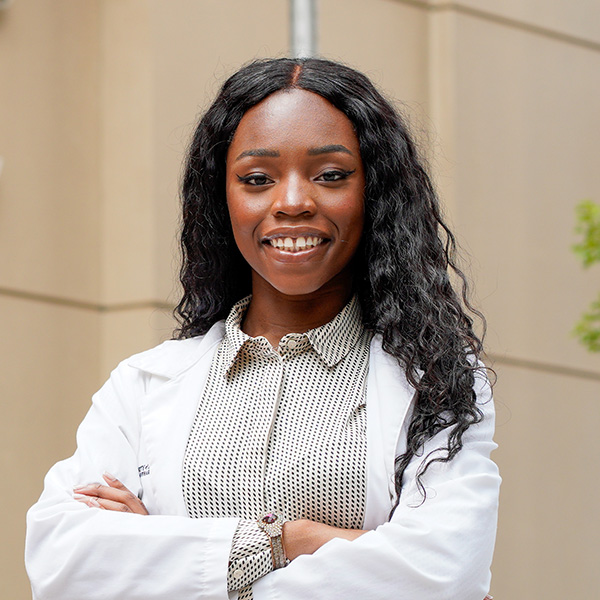 A student pharmacist standing outside Pharmacy Hall.