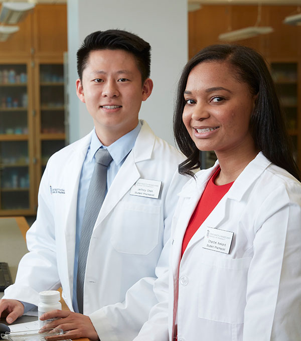 Two student pharmacists wearing white coats