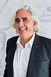 Marcus Knoll posing indoors with a dark jacket against a marbled background