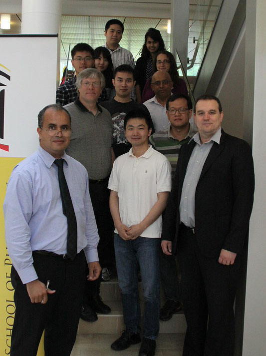 Group of people standing together on an indoor staircase and landing, posing for a photo next to a banner