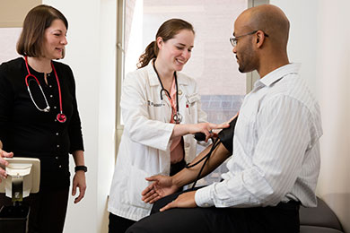 Preceptor oversees student as she takes the blood pressure of a patient.