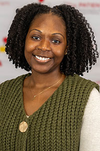 Portrait of Andrelle Mathelier wearing a green shirt, smiling in front of a white background with the PATIENTS Program logo