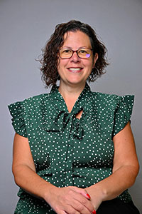 Michelle Medeiros wearing a green patterned blouse and seated against a plain background