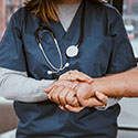 Doctor holds hands with patient.